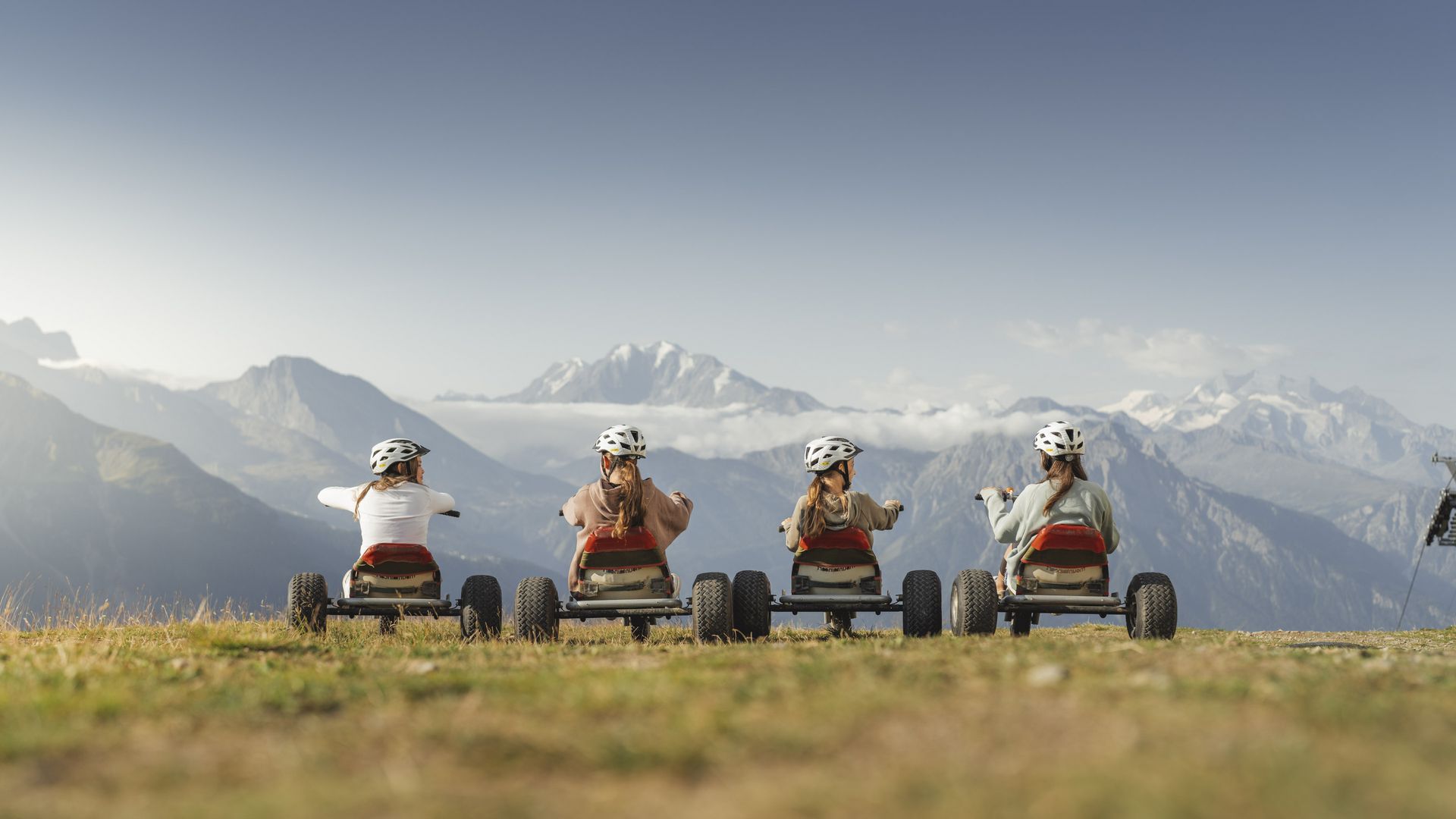 Quatre amies sont assises sur des VTT en été à Riederalp Suisse et contemplent les hauts sommets valaisans.