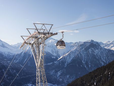 Une télécabine est suspendue au mât devant un panorama alpin. Ce téléphérique complète idéalement l'arrivée et la mobilité Aletsch Arena.