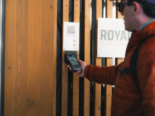 Ein Mann scannt mit seinem Smartphone einen QR-Code, um das Gebäude für das Coworking Riederalp zu betreten.