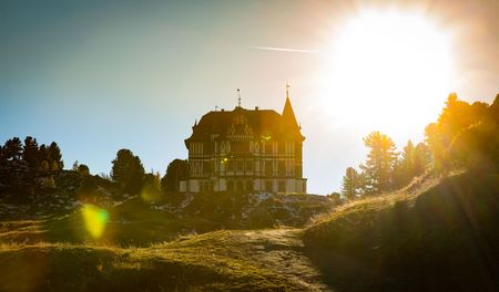 Villa Cassel im warmen Gegenlicht zwischen Bäumen und Wiesen auf der Seite Nachhaltigkeit Aletsch Arena.
