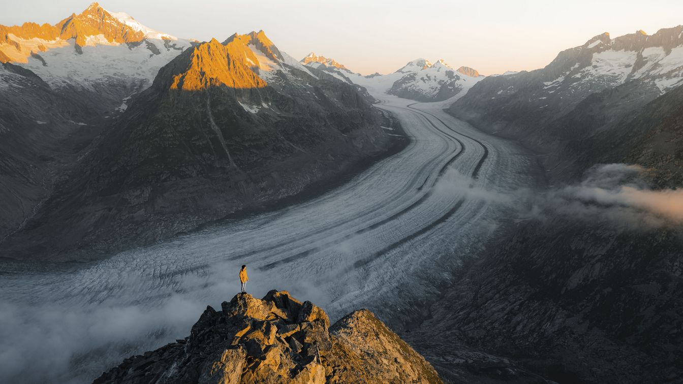 Person steht auf Felsen und blickt über den Aletschgletscher bei der Fiescheralp in der Aletsch Arena