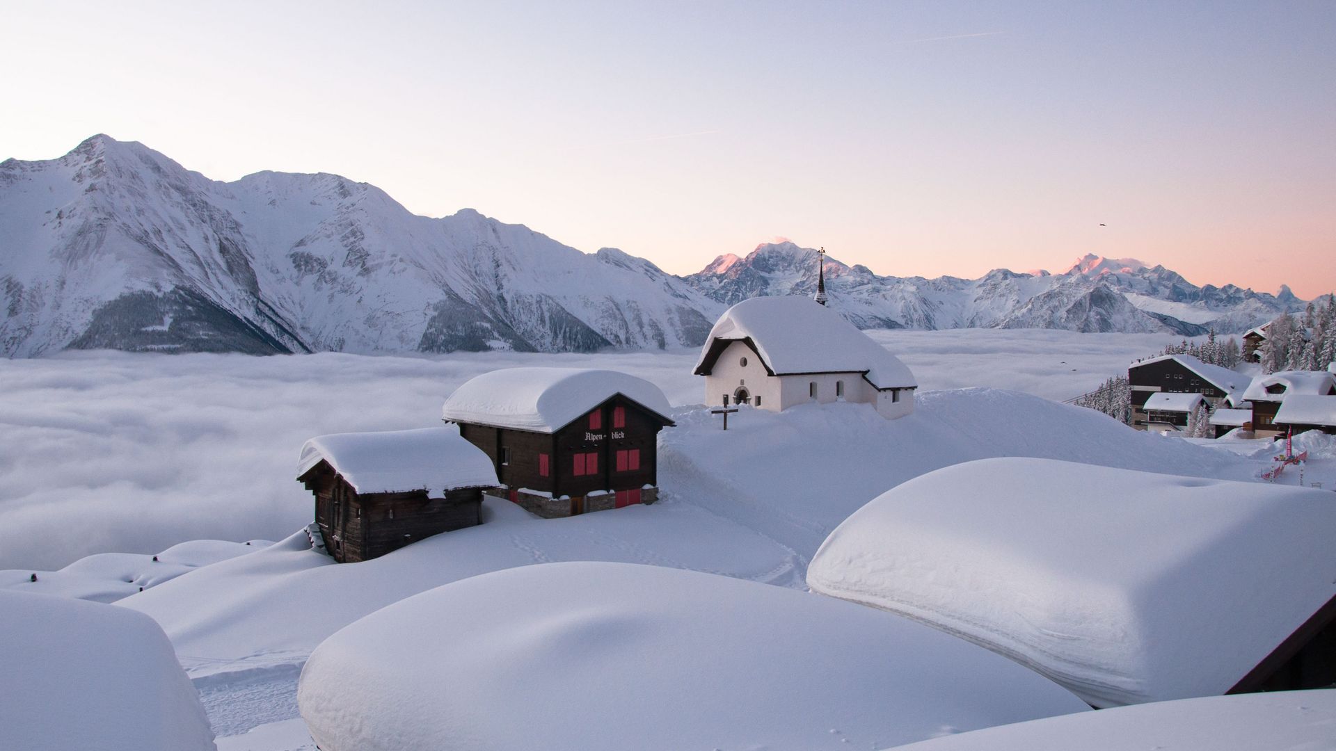 Weihnachten bei der Kapelle Maria zum Schnee mit tief verschneiten Häusern, Nebelmeer mit sanftem Abendlicht.
