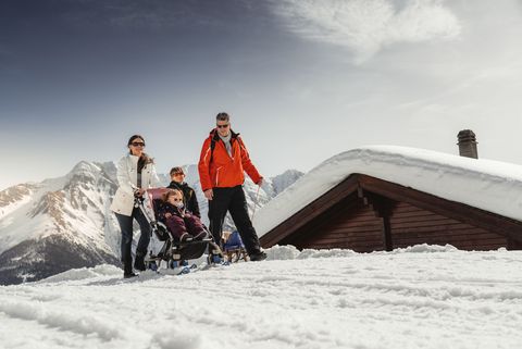 Familie mit Kinderwagen und Schlitten im Schnee auf der Seite Auszeichnungen Aletsch Arena.