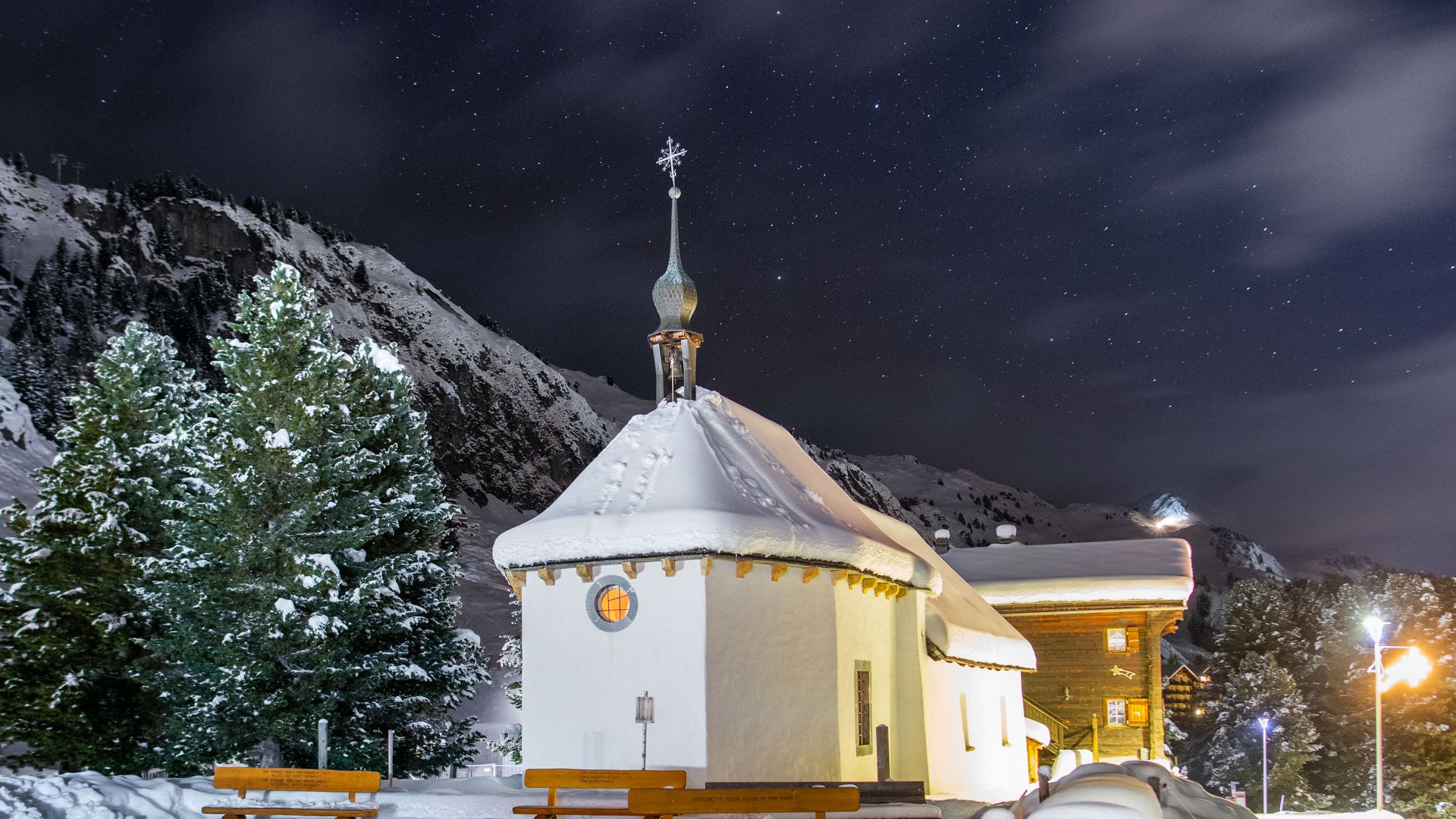 La chapelle illuminée et enneigée du Saint-Bernard sur la Riederalp Suisse, par nuit claire, sous un ciel étoilé.