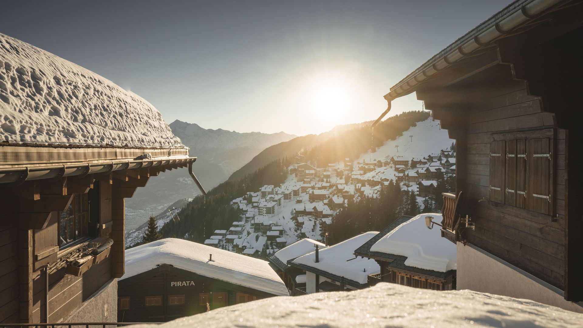 Vue entre les chalets en bois enneigés sur le village profondément enneigé de Bettmeralp Suisse, éclairé par le soleil.