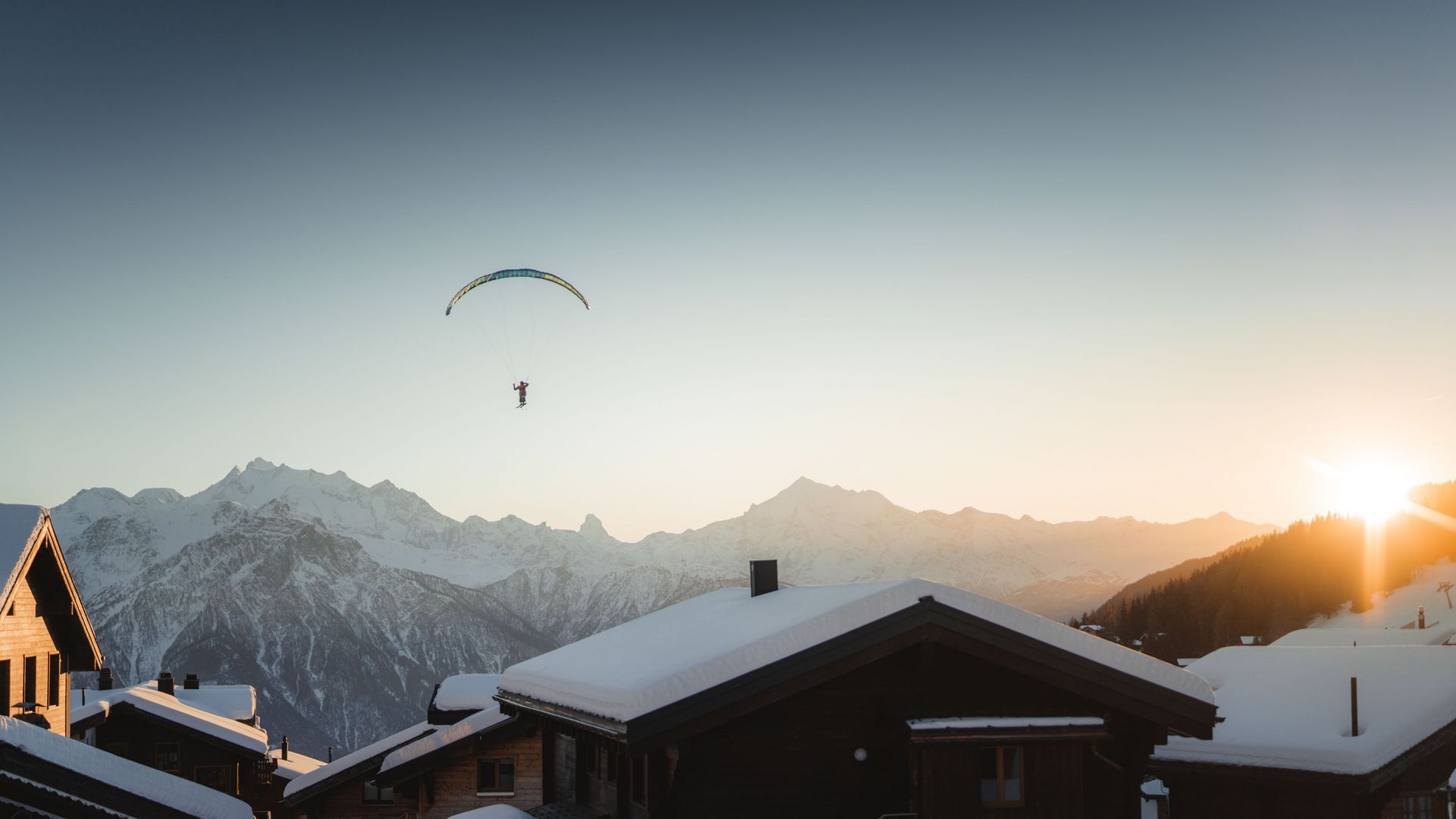 Parapente au-dessus de Bettmeralp, devant les Alpes enneigées, dans la chaleur du coucher de soleil.