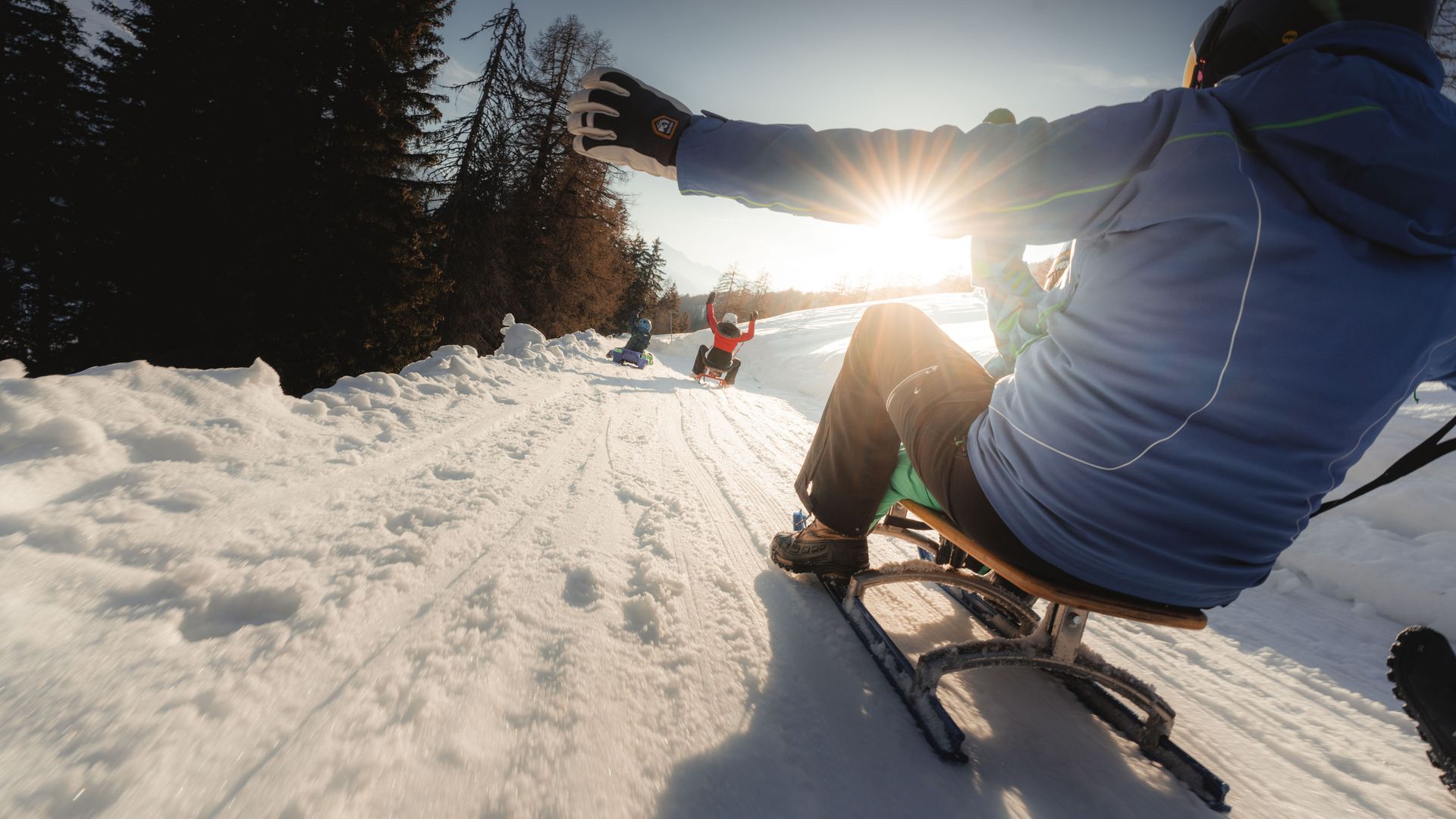 Bei sonnigem Winterwetter geniessen mehrere Personen die Schlittelpiste Fiescheralp nach Lax.