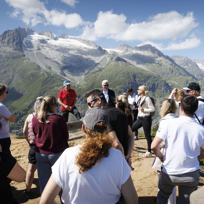 Eine Wandergruppe geniesst bei einem Retreat Aletsch Arena die weite Aussicht auf den majestätischen Gletscher.