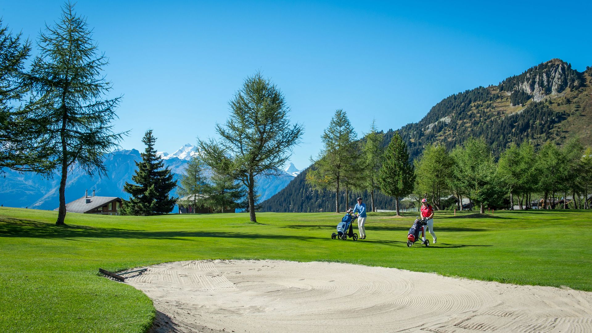 Deux golfeurs poussent leurs chariots sur le fairway, lors d'une partie de golf à Riederalp.