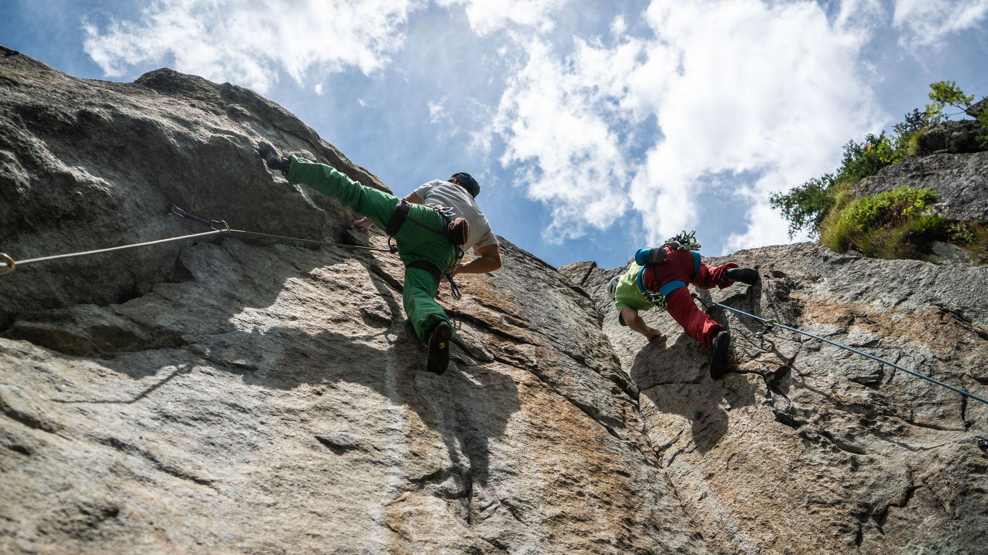 Deux grimpeurs escaladent une paroi rocheuse en étant assurés et découvrent l'escalade dans l'Aletsch Arena sur des voies exigeantes.