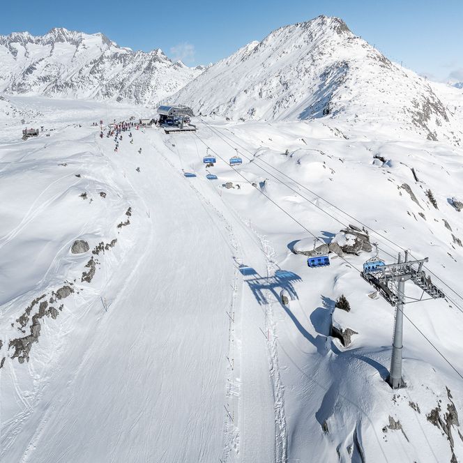 Télésiège moderne au-dessus de pistes préparées dans la neige, idéal pour faire du ski dans l'Aletsch Arena.