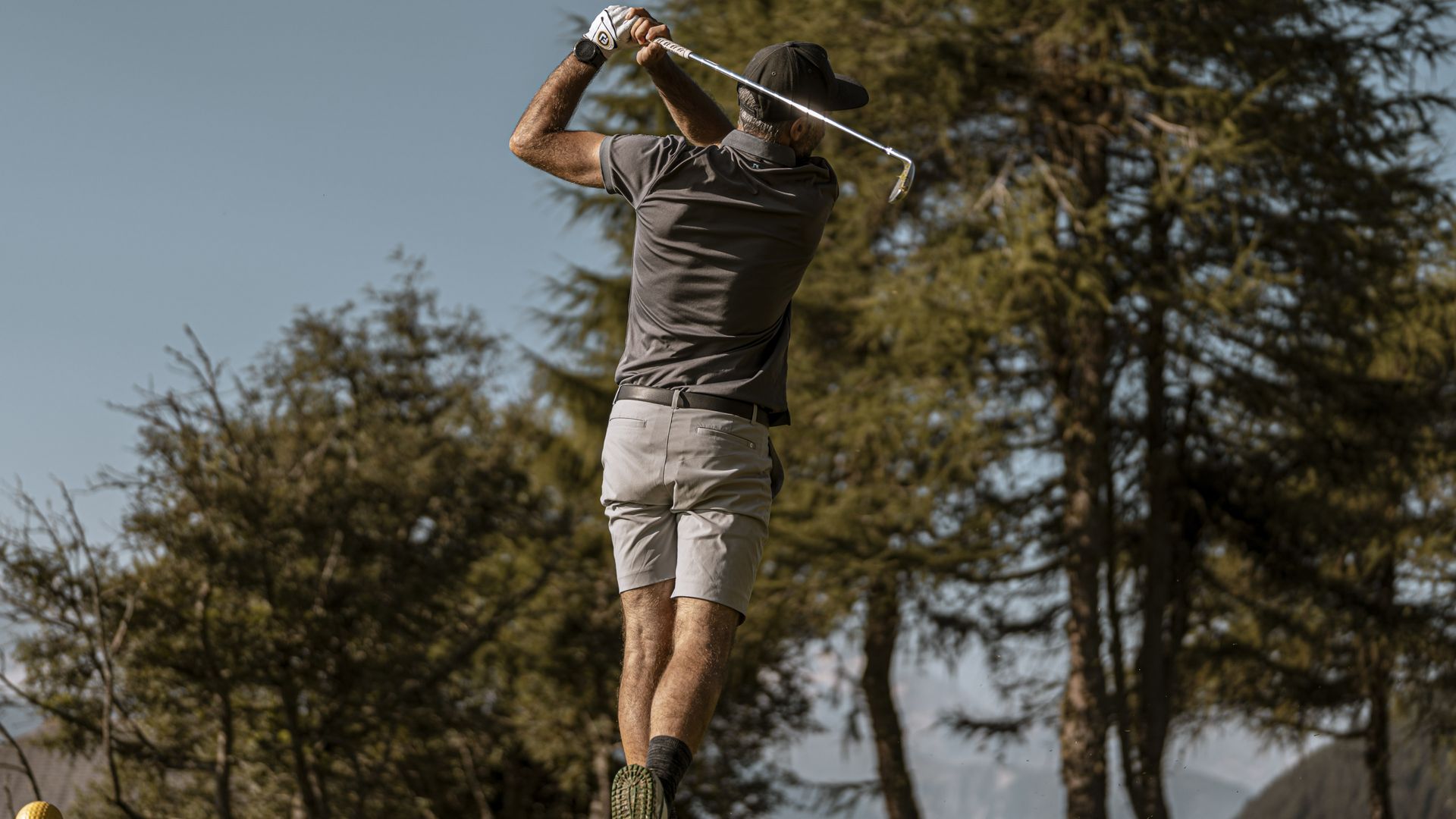 Un golfeur suit du regard sa balle après son coup de départ sur le tee et profite du Golf Riederalp au cœur d'un paisible paysage de montagne.