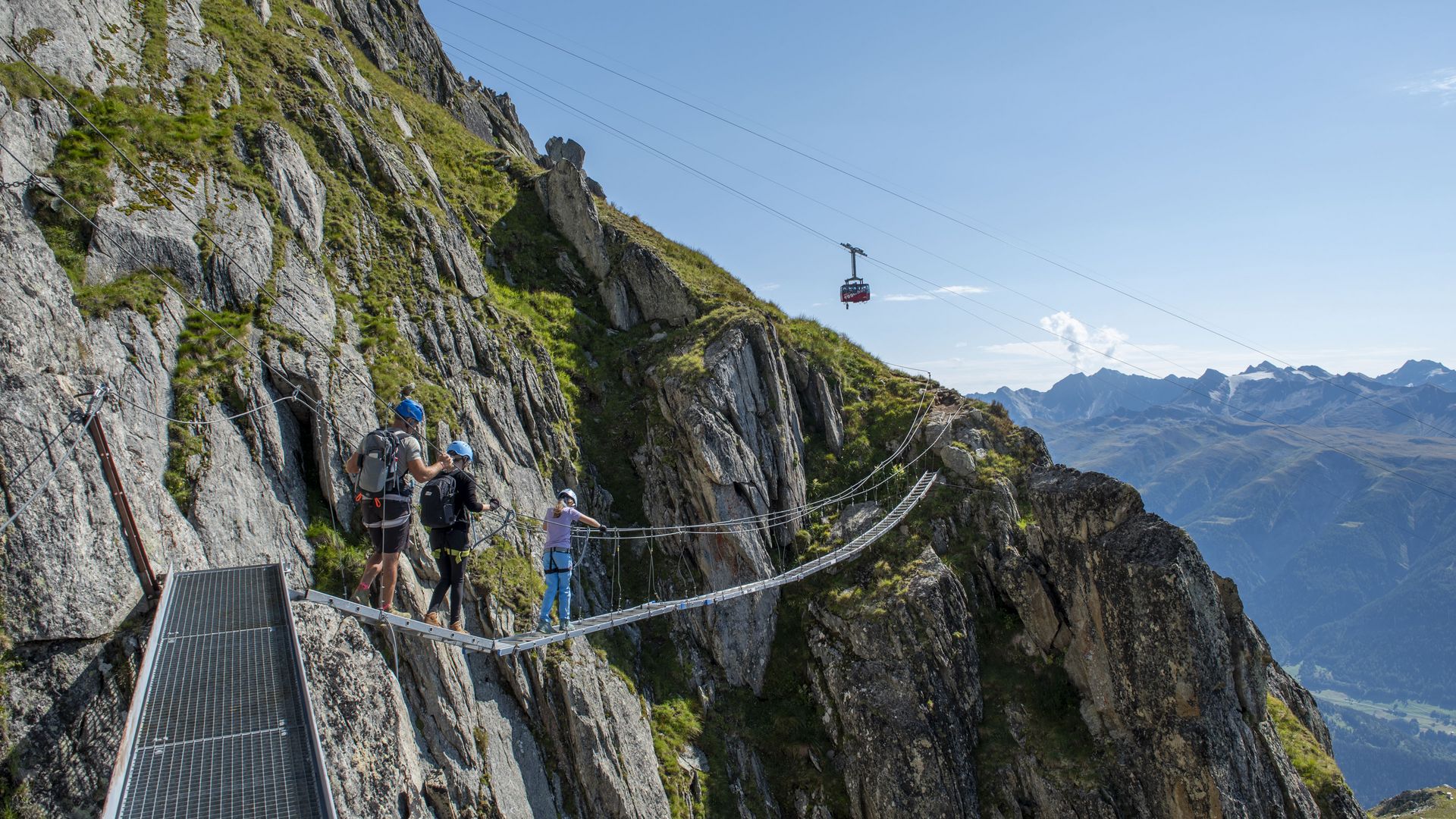 Une famille traverse en toute sécurité un pont suspendu sur la via ferrata de l'Eggishorn.
