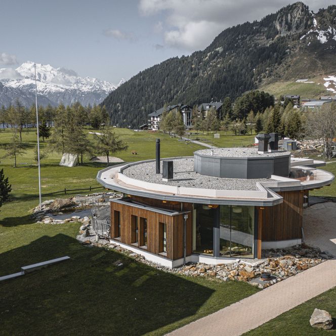 Ein rundes Holzgebäude mit grossen Fenstern dient als inspirierende Basis für das Retreat Aletsch Arena im Sommer.