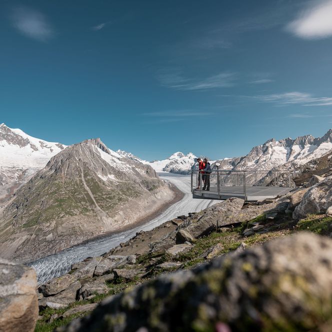 En été, un couple contemple l'immense glacier d'Aletsch depuis la plate-forme panoramique près de Fiesch, en Suisse.