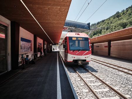 Un train rouge s'arrête sur le quai. L'accès et la mobilité Aletsch Arena sont parfaitement adaptés à la circulation des trains.