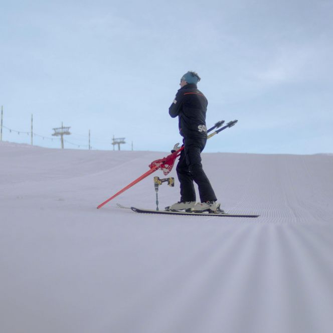 Jobs Aletsch Bahnen AG: Person der Pistenrettung fährt mit roten Schlittenholmen über eine präparierte Piste.
