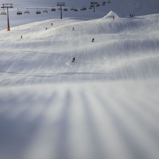 Les skieurs glissent avec élan sur une piste ondulée ensoleillée. Une journée magnifique dans l'Aletsch Arena d'hiver.