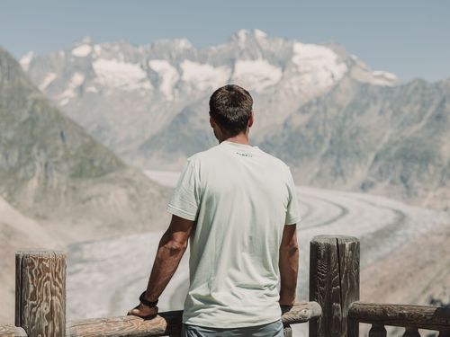 Ein Mann blickt in einer Pause vom Coworking Riederalp vom View Point Moosfluh auf den riesigen Aletschgletscher.