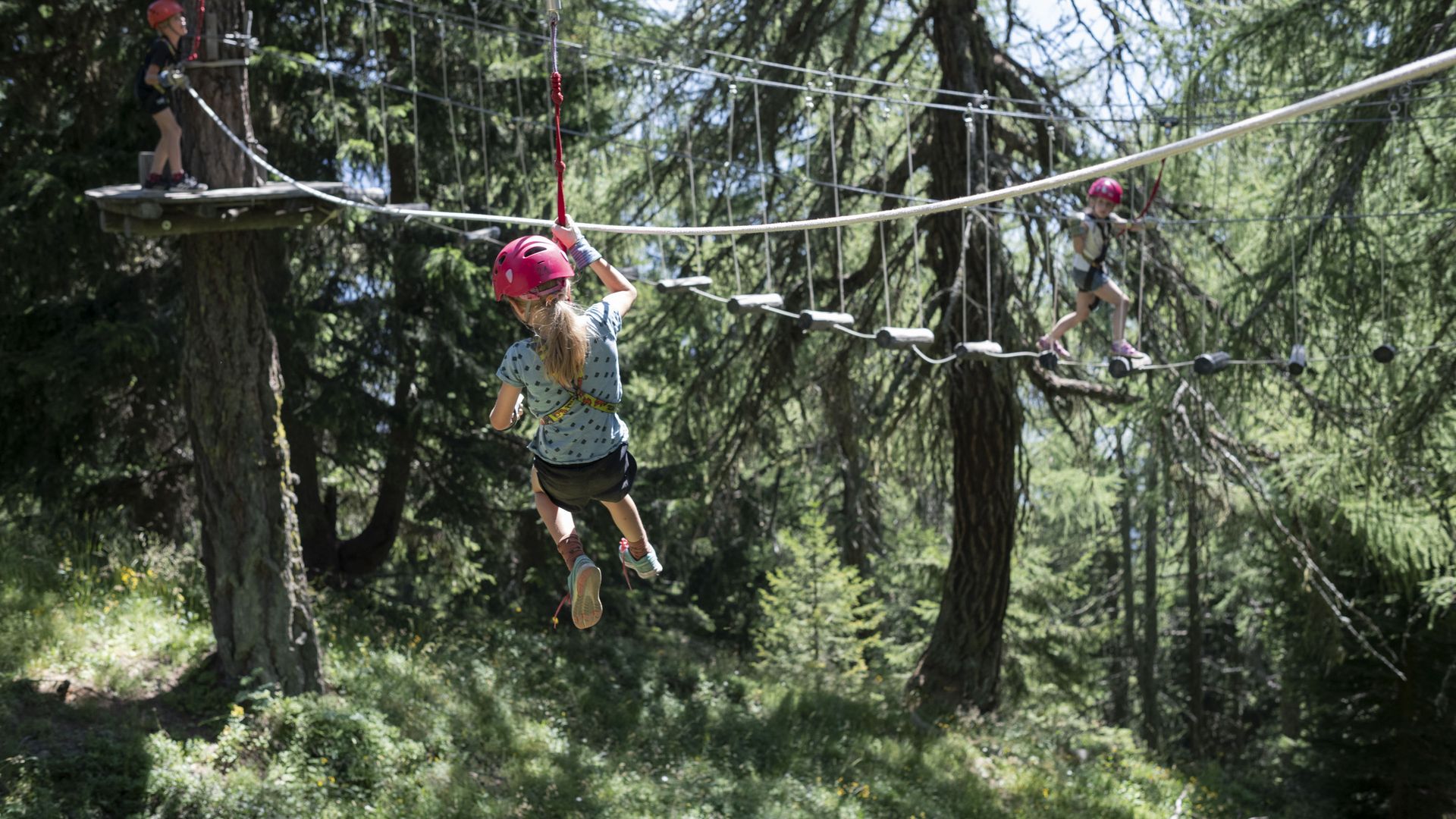 Dans la forêt, les enfants évoluent en toute sécurité sur des cordes et des obstacles et découvrent des parcours passionnants en grimpant dans l'Aletsch Arena.