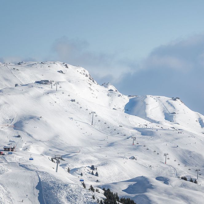 Un télésiège moderne mène sur de vastes pistes de ski blanches, haut dans les montagnes ensoleillées de l'Aletsch Arena d'hiver.
