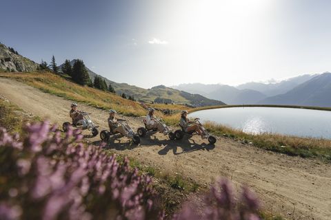 Vier Personen fahren als aktive Pause beim Retreat Aletsch Arena mit Mountaincarts an einem See vorbei.