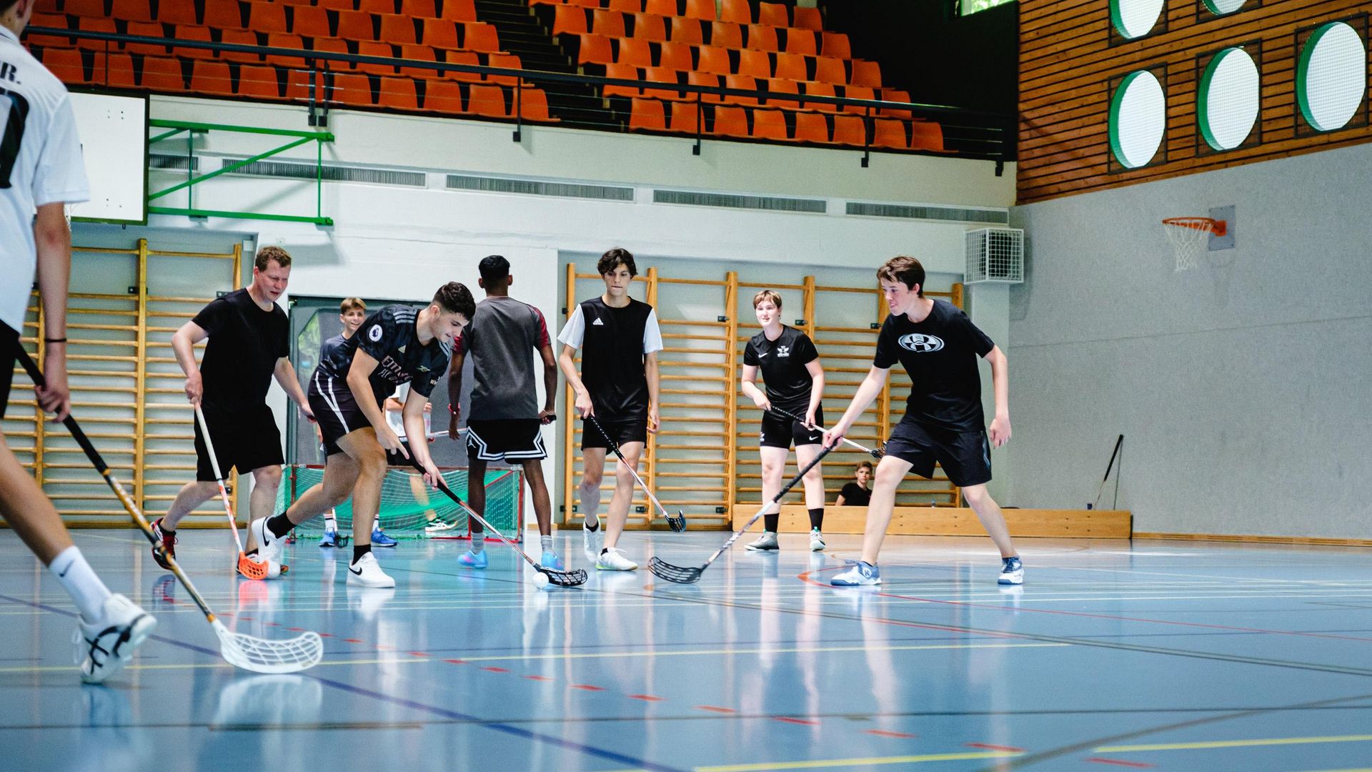 Des jeunes jouent à l'unihockey dans une salle de sport dans le cadre des offres de groupe diversifiées de l'Aletsch Arena.