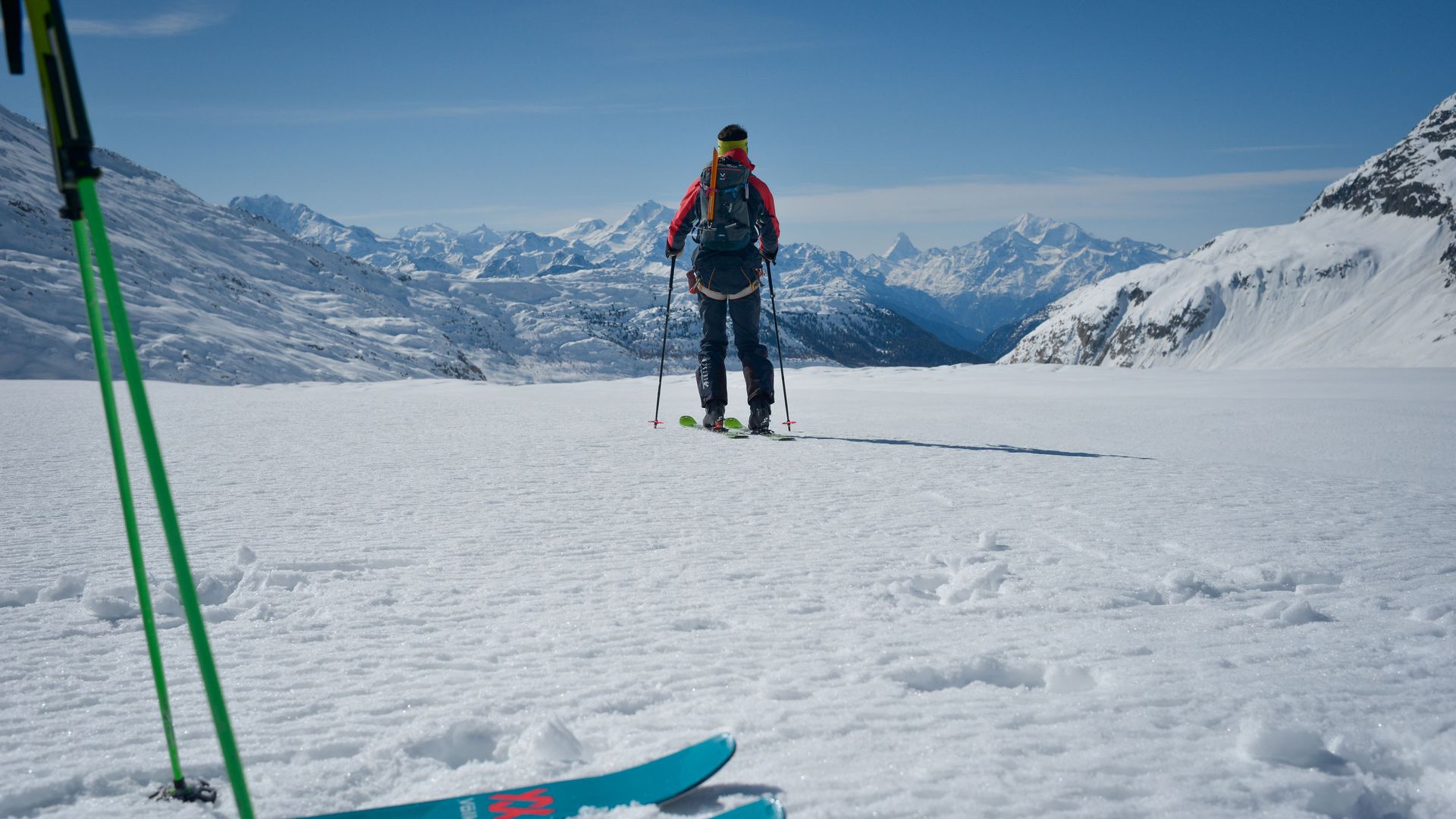 Ski tourers in the Aletsch Arena on a vast snowfield with a view of the snow-covered Valais Alps.