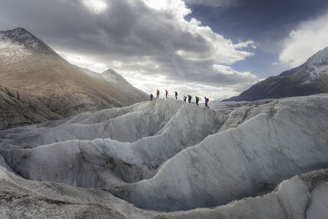 Gruppe auf einem Eisrücken zwischen Gletscherspalten auf der Seite Auszeichnungen Aletsch Arena.
